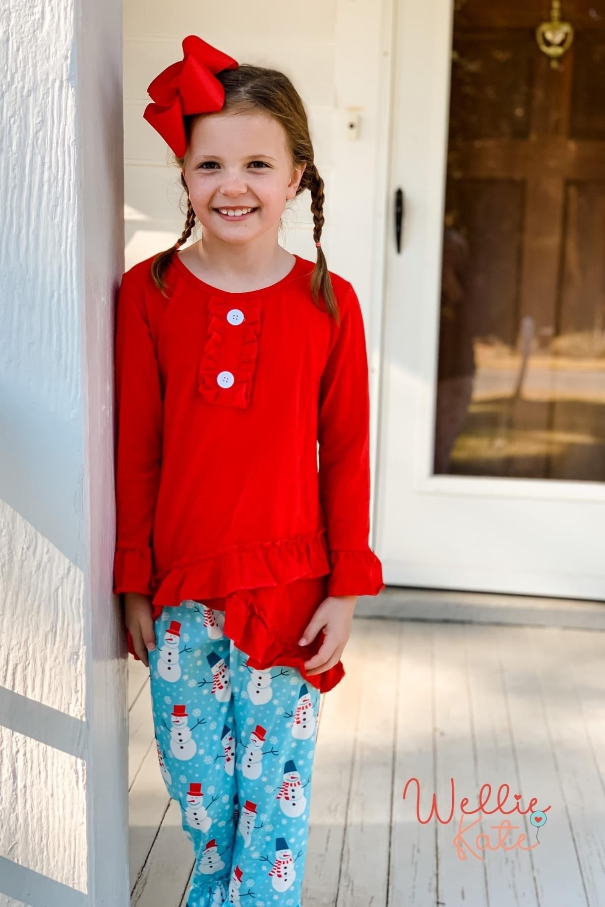 Girl wearing red top and snowman pants
