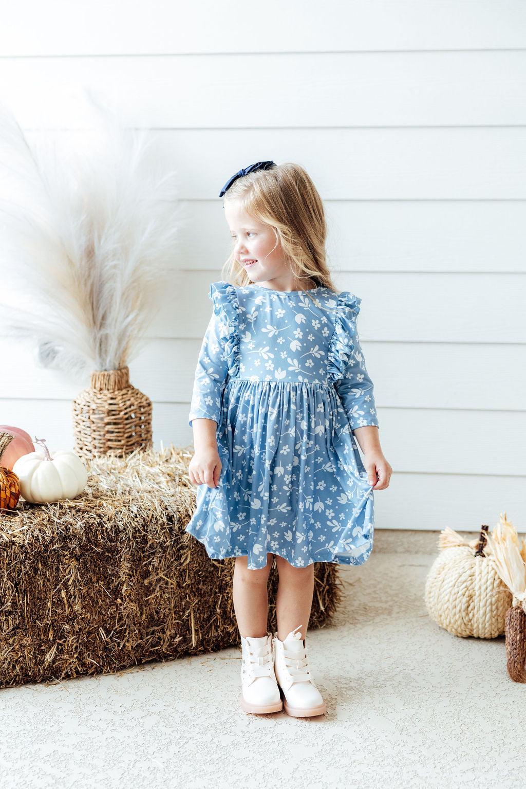 Girl wearing blue dress with ruffles on bodice and white flowers