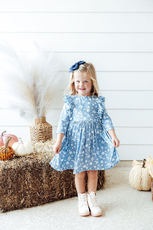 Girl wearing blue dress with ruffles on bodice and white flowers