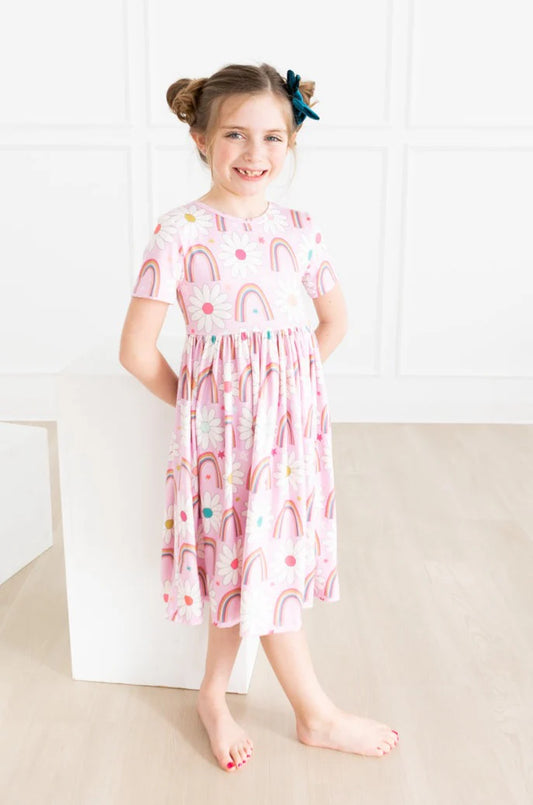 Girl wearing pink dress with rainbows and daisies