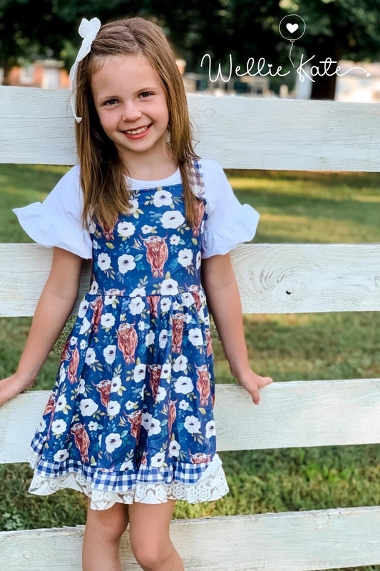 Girl wearing highland cow dress and leaning on fence