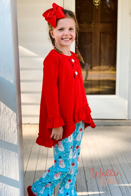 Girl wearing red top and snowman pants 